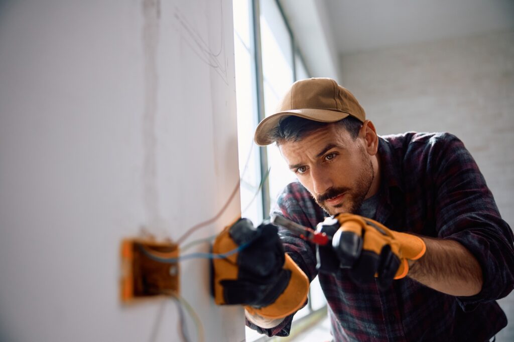 Worker installing electric cables during housing remodeling process.