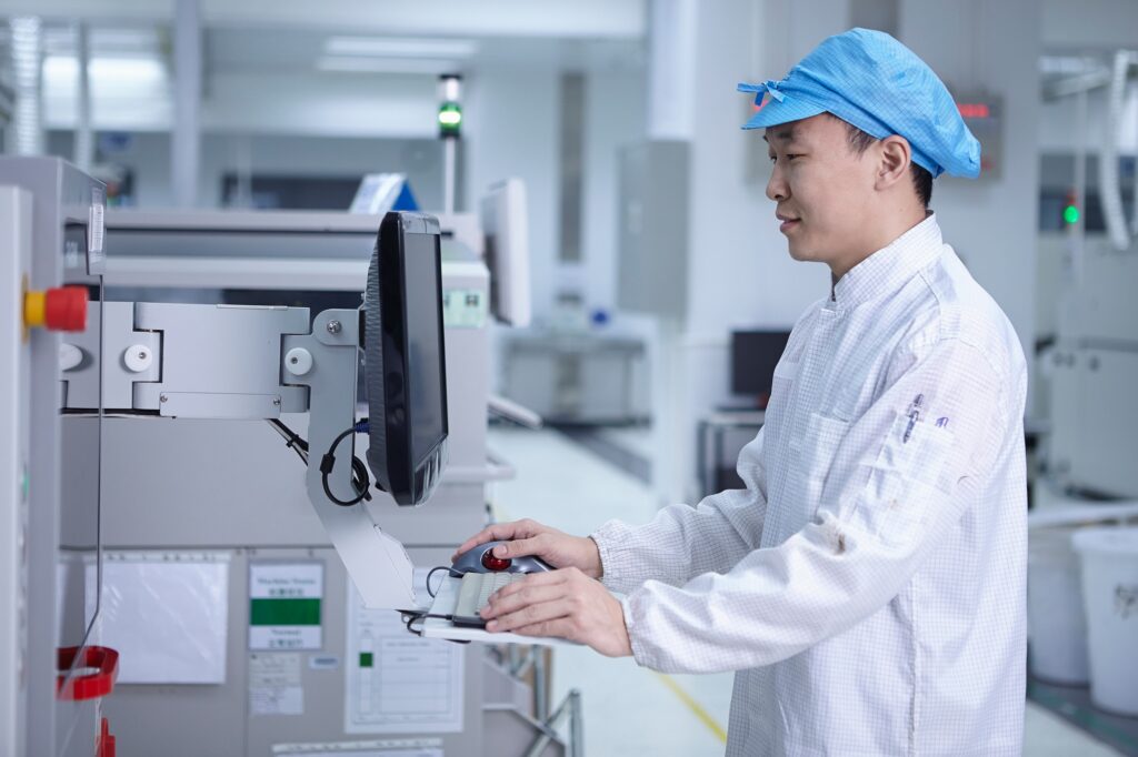 Worker using computer in factory that specialises in creating functional circuits on flexible